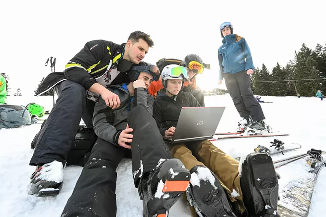 Students with computer on ski slope
