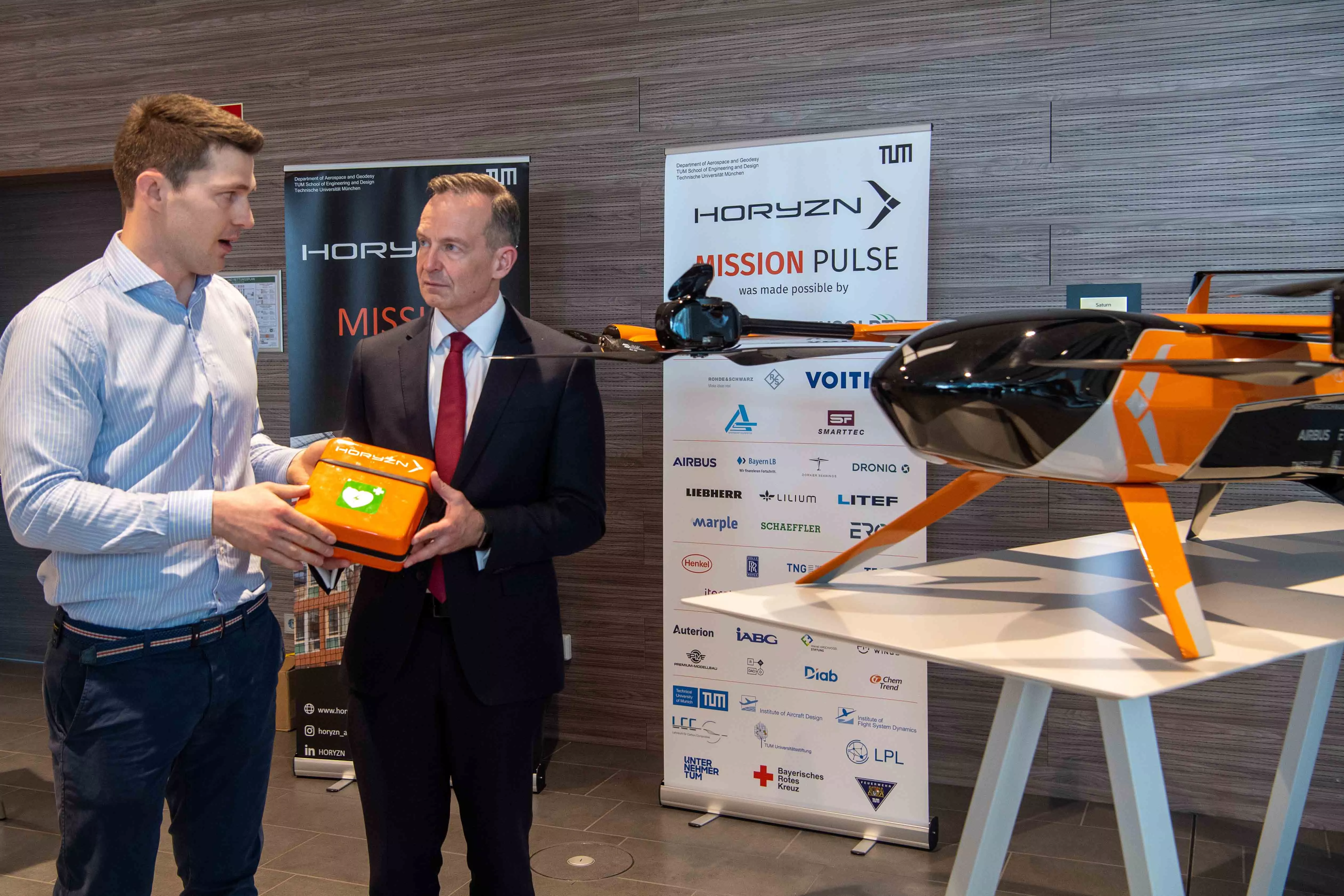 Bundesverkehrsminister Dr. Volker Wissing mit dem Defibrillator der Horyzn-Drohne. Projekleiter Balázs Nagy erklärt das Konzept. 