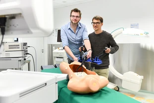 Zwei Personen die einen Roboter in einem Operationssaal testen