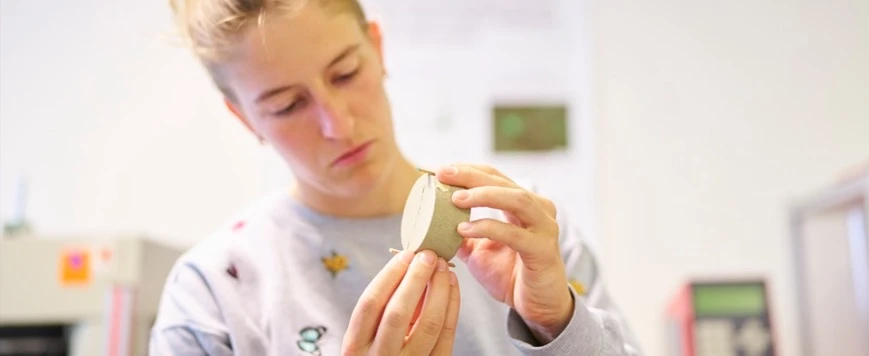 Forschende begutachtet etwas in ihren Händen im Labor.